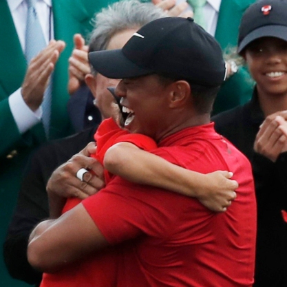 Golf - Masters - Augusta National Golf Club - Augusta, Georgia, U.S. - April 14, 2019 - Tiger Woods of the U.S. embraces his son Charlie Axe as his daughter Sam Alexis (R) looks on after he won the 2019 Masters.